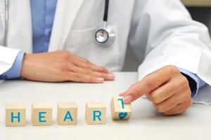 en bois bloquer avec mot cœur, main de médecin en portant une en bois bloquer cube avec cœur taux icône symbole. médical et santé concept. photo