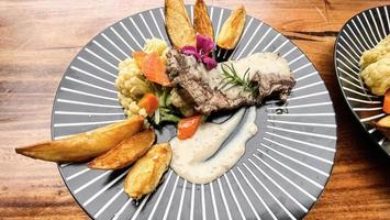 juteux du boeuf steak avec salade et Patate coins le long de avec poivre blé sauce photo