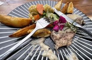 juteux du boeuf steak avec salade et Patate coins le long de avec poivre blé sauce photo