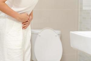 constipation et diarrhée dans la salle de bain. blesser la femme toucher le ventre mal de ventre douloureux. problème d'inflammation du côlon, aliments toxiques, douleurs abdominales, abdomen, toilettes constipées, maux de ventre, hygiène photo