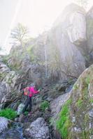 femme promeneur en dessous de une cascade dans le rochers photo