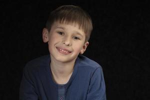 portrait de une dix ans garçon sur une foncé Contexte. le enfant regards dans le caméra avec intelligent yeux. Beau garçon de école âge. photo