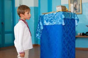 une peu biélorusse ou ukrainien garçon dans un brodé chemise dans une église. photo