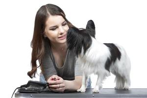 une mignonne Jeune femme est étreindre sa papillon chiot. l'amour entre propriétaire et chien. fille avec chien studio portrait. photo