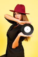 fille dans une noir costume sur une Jaune Contexte avec une record dans sa mains, musique, le fille spectacles émotions photo