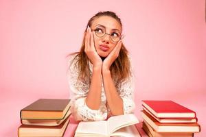 rose arrière-plan, une fille lit livres, une livre amoureux, une étudiant mensonges sur le sol parmi une grand nombre de livres photo