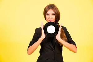 fille dans une noir costume sur une Jaune Contexte avec une record dans sa mains, musique, le fille spectacles émotions photo