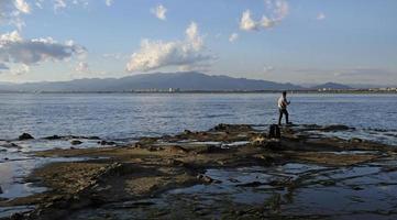 paysage spectaculaire sur la côte d'enoshima, au japon, avec un pêcheur solitaire debout au bord de l'eau photo