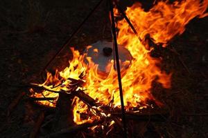 cuisiner à l'extérieur dans des conditions de terrain. chaudron sur un feu dans la forêt. cuisiner sur le bûcher en voyageant. trépied avec un chapeau melon sur un feu en pique-nique. voyage conceptuel, trekking et aventure photo