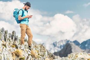 Jeune homme poignées téléphone intelligent pendant dans alpin randonnée photo