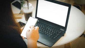 femme séance et travail avec une carnet ordinateur et utilisation une mobile téléphone affaires femme concept le long de avec le téléphone écran coupure chemin et le carnet écran photo