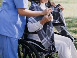 asiatique Jeune soignant infirmière soutien Sénior plus âgée Masculin en marchant en plein air. spécialiste fille médecin Aidez-moi et prendre se soucier de personnes âgées mature homme patient Faire physique thérapie dans Publique parc à allaitement maison. photo