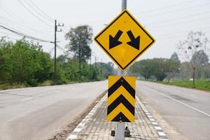 Jaune avertissement route signe avec symbole de flèches sur le route pour le deux façon courir dans rural de Thaïlande. concept , avertissement circulation signe pour transport. photo