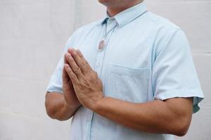 gros plan homme en chemise bleue, porte l'amulette de bouddha, priant avec les mains bouddhiste prier geste. wai dans la culture thaïlandaise. concept, wearship pour la chance, la foi et la croyance. modèle de respect et de salutation. photo