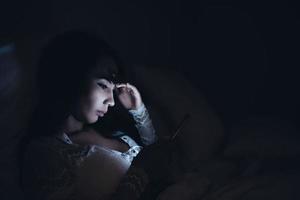 femme asiatique jouant au jeu sur smartphone dans le lit la nuit, thaïlande, toxicomane médias sociaux photo