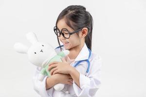 Asie peu fille en jouant médecin isolé sur blanc photo