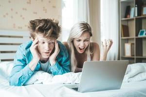 couple heureux utilisant un ordinateur portable sur le lit