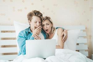 couple heureux utilisant un ordinateur portable sur le lit