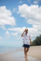 homme hipster marche sur le fond de la belle plage avec des nuages blancs et beau ciel photo