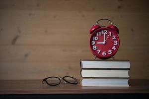 Réveil à 9h sur pile de livres avec des lunettes sur table en bois photo