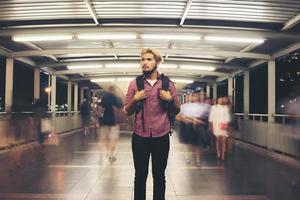 Bel homme barbu avec sac à dos debout dans la rue voyageant la nuit photo