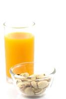 pistaches dans une assiette en verre et verre de jus d'orange isolé sur blanc