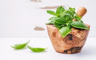 herbes dans un mortier en bois sur blanc minable photo