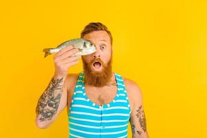homme avec barbe et maillot de bain pris une poisson photo