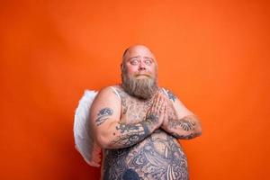 graisse peur homme avec barbe , tatouages et ailes actes comme un ange photo