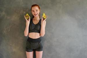 athlétique fille avec Gym vêtements mange Avocat à Accueil photo