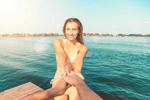 point de vue de une Jeune femme dans une maillot de bain ayant amusement avec sa partenaire à le mer photo