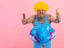 graisse homme avec barbe et perruque mange une popsicle et un crème glacée photo