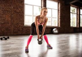 blond fille travail en dehors à le Gym avec une kettlebell photo