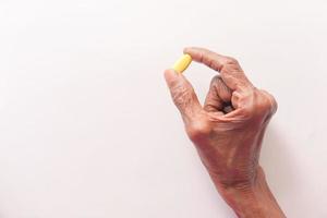 main de la personne âgée tenant la pilule jaune