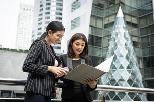 Businesswomen discuter de la paperasse ensemble contre la balustrade photo