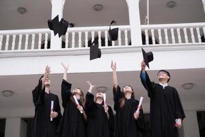 Groupe d'étudiants réussis jetant des chapeaux de graduation en l'air et célébrant photo