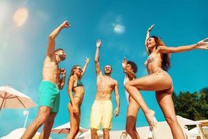 groupe de copains dans maillot de bain Danse la musique dans une nager bassin photo