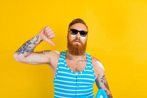 homme avec tatouages et maillot de bain met sur crème solaire photo