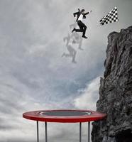 homme d'affaire sauter sur une trampoline à atteindre le drapeau. réussite affaires objectif et difficile carrière concept photo