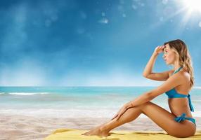 fille dans bikini est assis sur une plage à la recherche pour Nouveau Voyage destination. photo