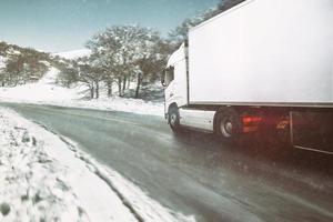 blanc moderne un camion en mouvement vite dans hiver sur une route avec neige photo