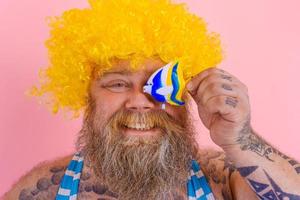 graisse content homme avec barbe et des lunettes de soleil avoir amusement avec une poisson jouet photo