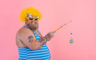 graisse content homme avec barbe et des lunettes de soleil avoir amusement avec le pêche pôle photo