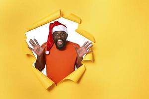 afro homme avec chapeau est content car est Noël. Jaune Contexte photo