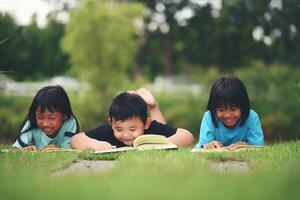 groupe de les enfants mensonge en train de lire sur herbe champ photo