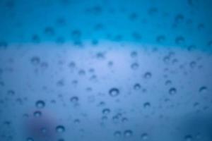 bleu l'eau gouttelettes et gouttes de pluie se cramponner à le cool clair verre photo