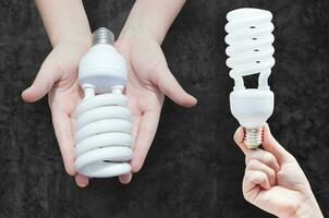 énergie économie concept, femme main en portant lumière ampoule sur foncé arrière-plan, idées lumière ampoule dans le main photo