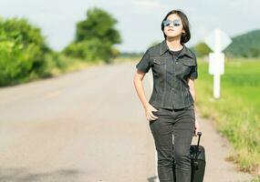 femme avec bagages faisant de l'auto-stop le long d'une route photo