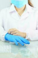 mains de scientifiques mettant des gants en latex bleu nitrile dans une blouse de laboratoire portant des gants en nitrile photo