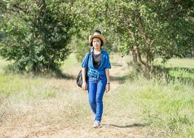 femme portant un chapeau marchant et portant son sac de guitare photo